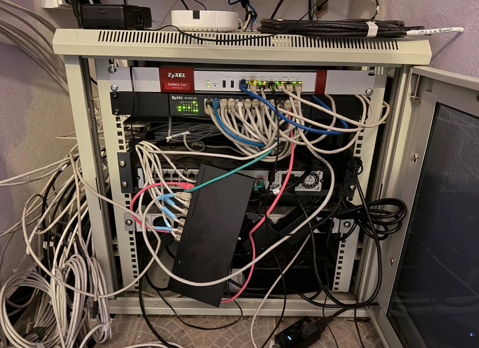 Přeplněný rack s kabely mimo skříň